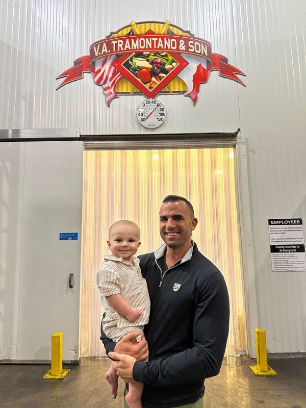 Chris Tramontano holding his son, Chris Jr., in front of the V.A. Tramontano & Son sign at our warehouse